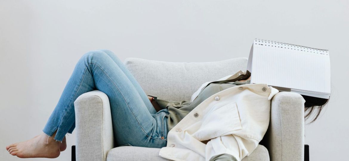 girl on the couch with a notebook on her face