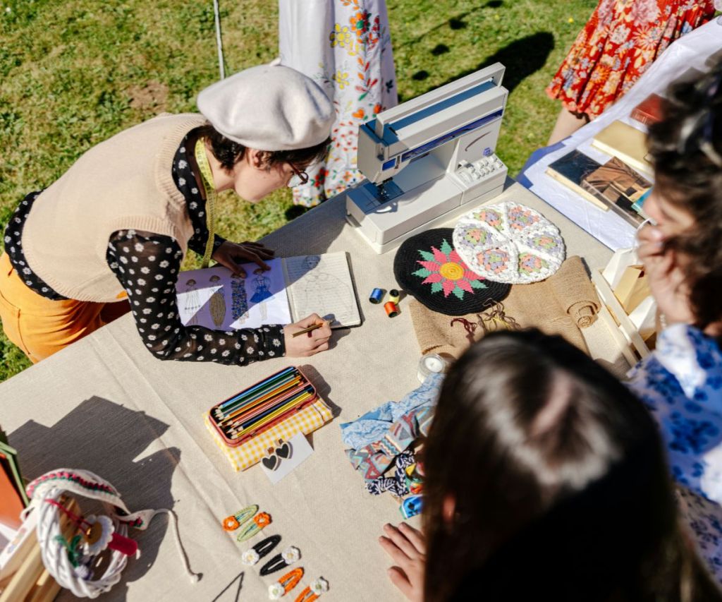 Person sketching fashion designs at an outdoor craft table