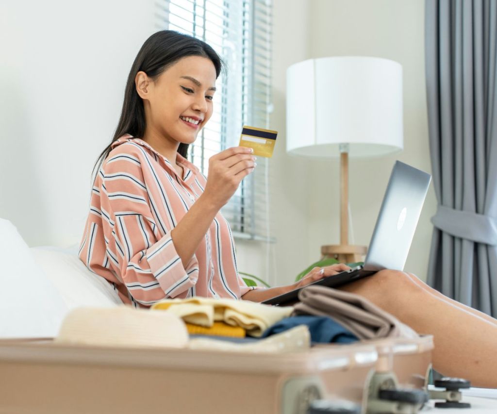 Traveler holding travel fund card while booking a trip online