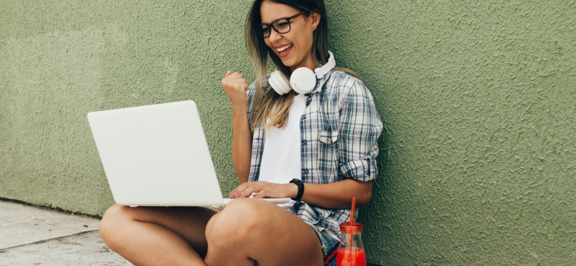Girl sitting on ground with laptop showing campaign success, planning next steps