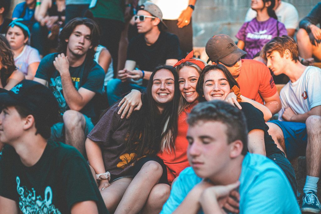 Three friends smiling in crowd.